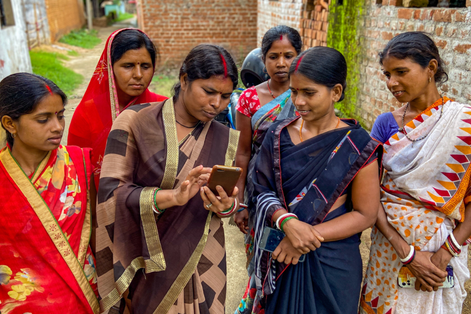 A group of women from rural India looking at the smartphone one of them is holding