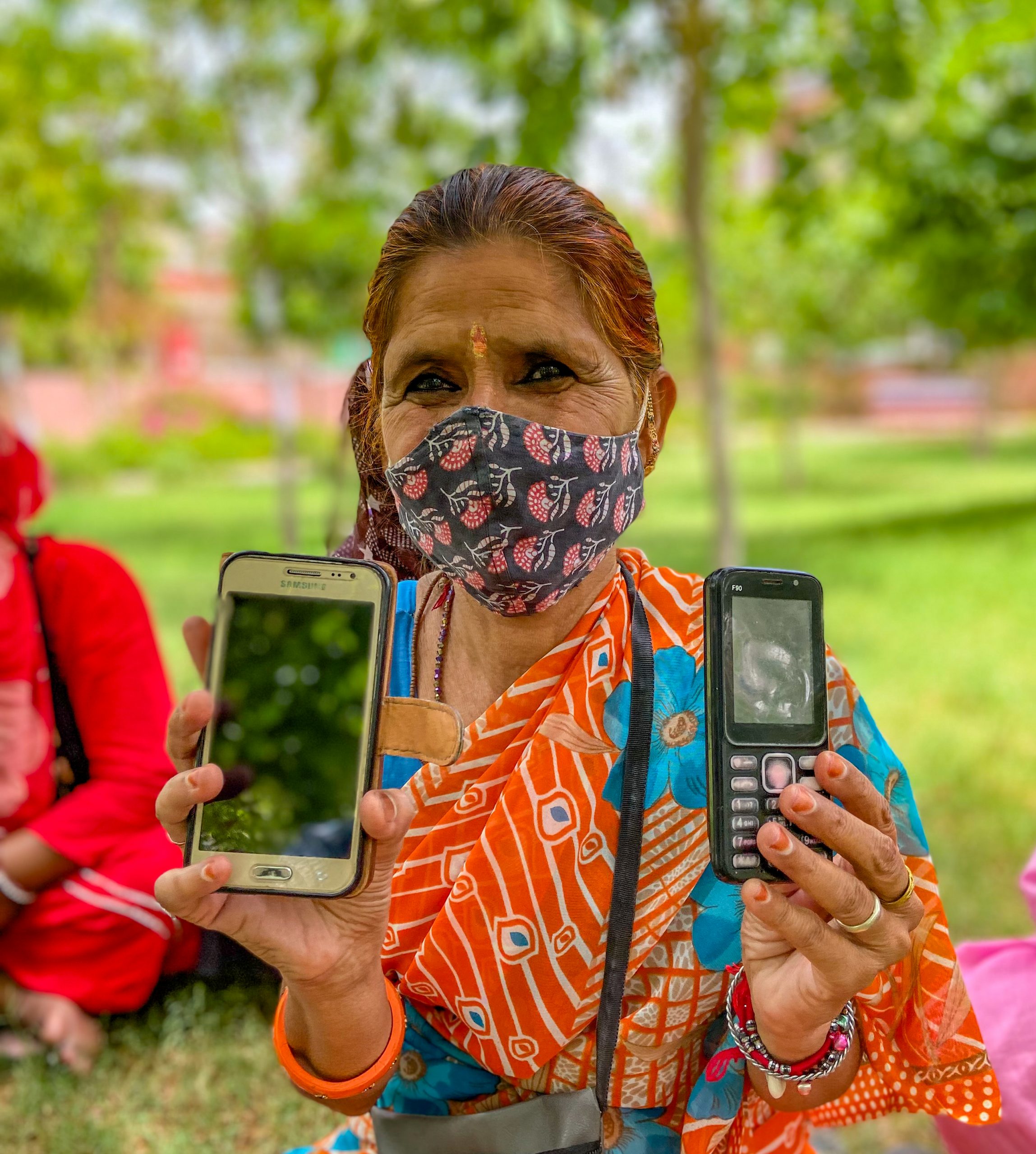 A woman shows her regular feature phone and smartphone