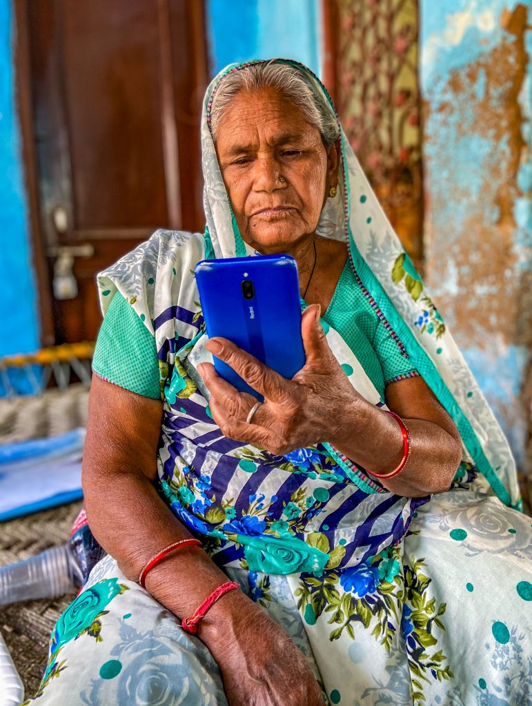An older woman without formal schooling taking digital literacy classes on a smartphone.