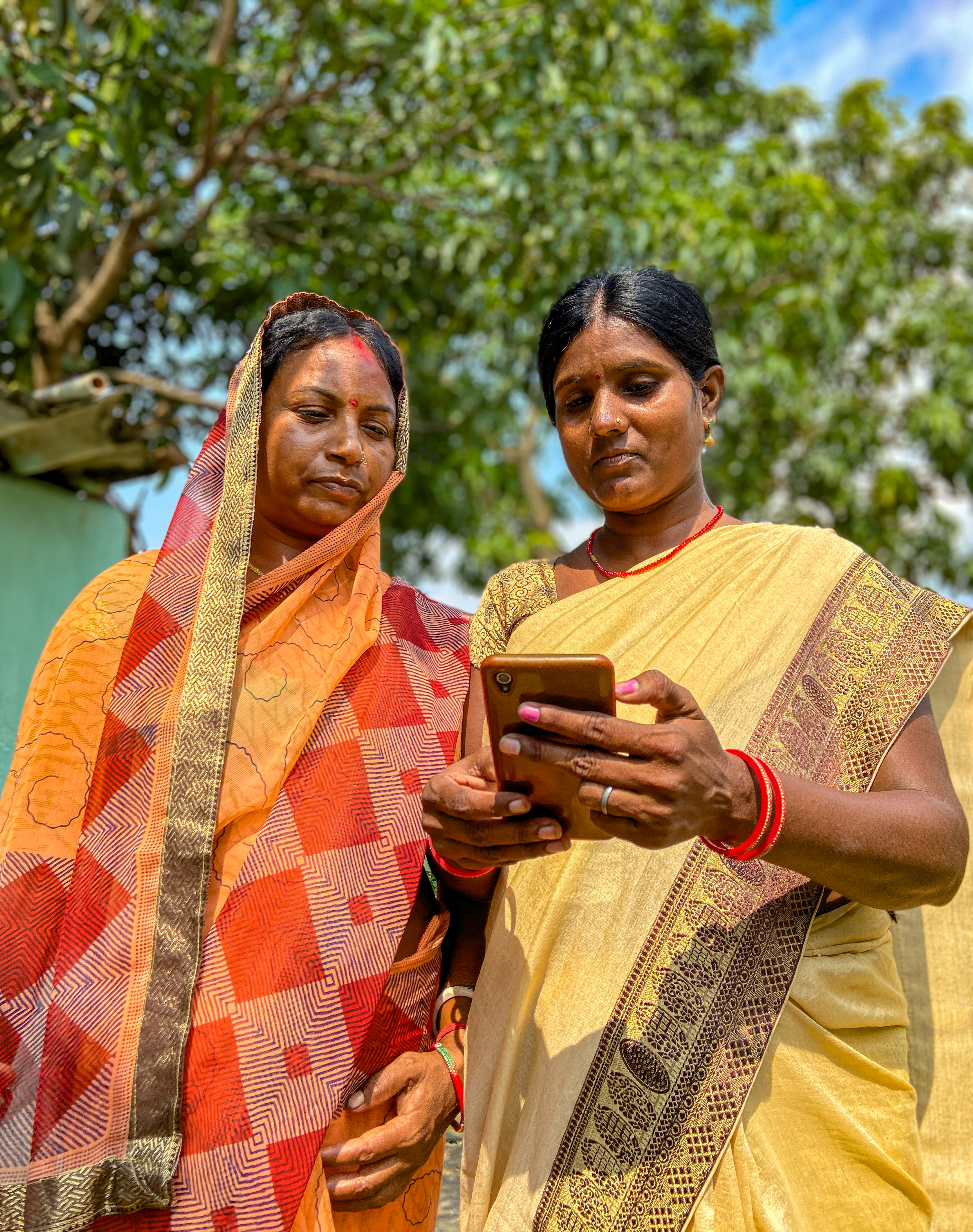Two women from rural India looking at the smartphone one of them is holding. 