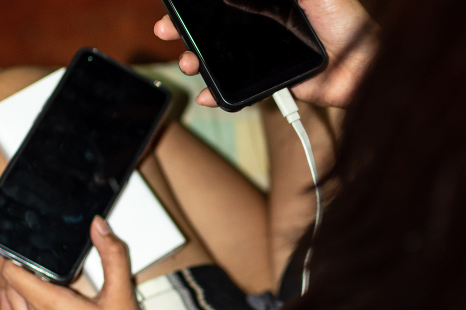 A woman charging her phone on a portable power bank to stay connected