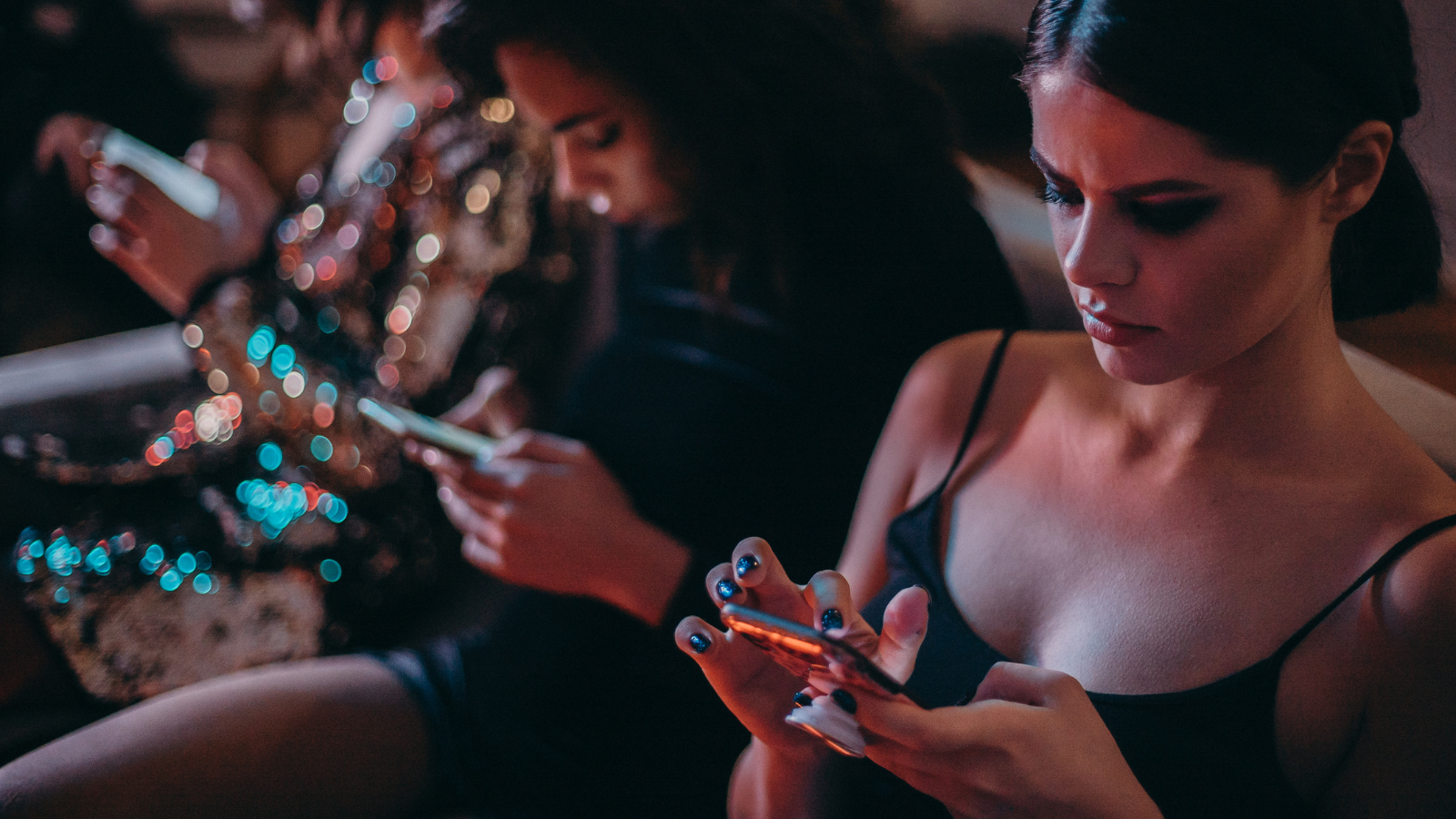 A group of women using their smartphones while sitting together