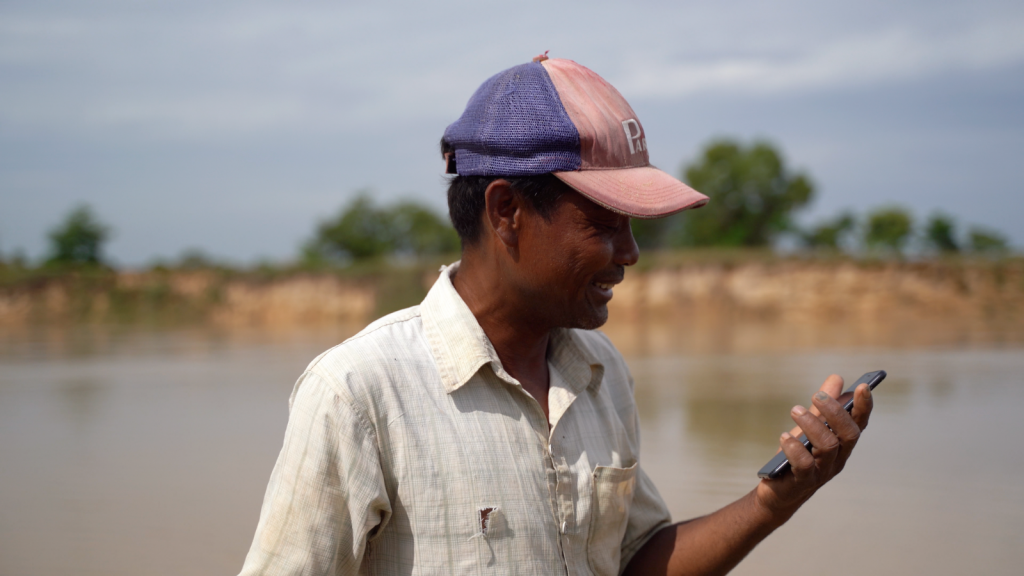 A man looking at his smartphone with climate Information and early warning systems, under UNDP Cambodia project