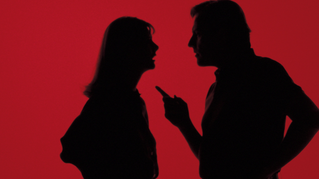 Silhouette of people arguing, with the man pointing his finger at the woman. 