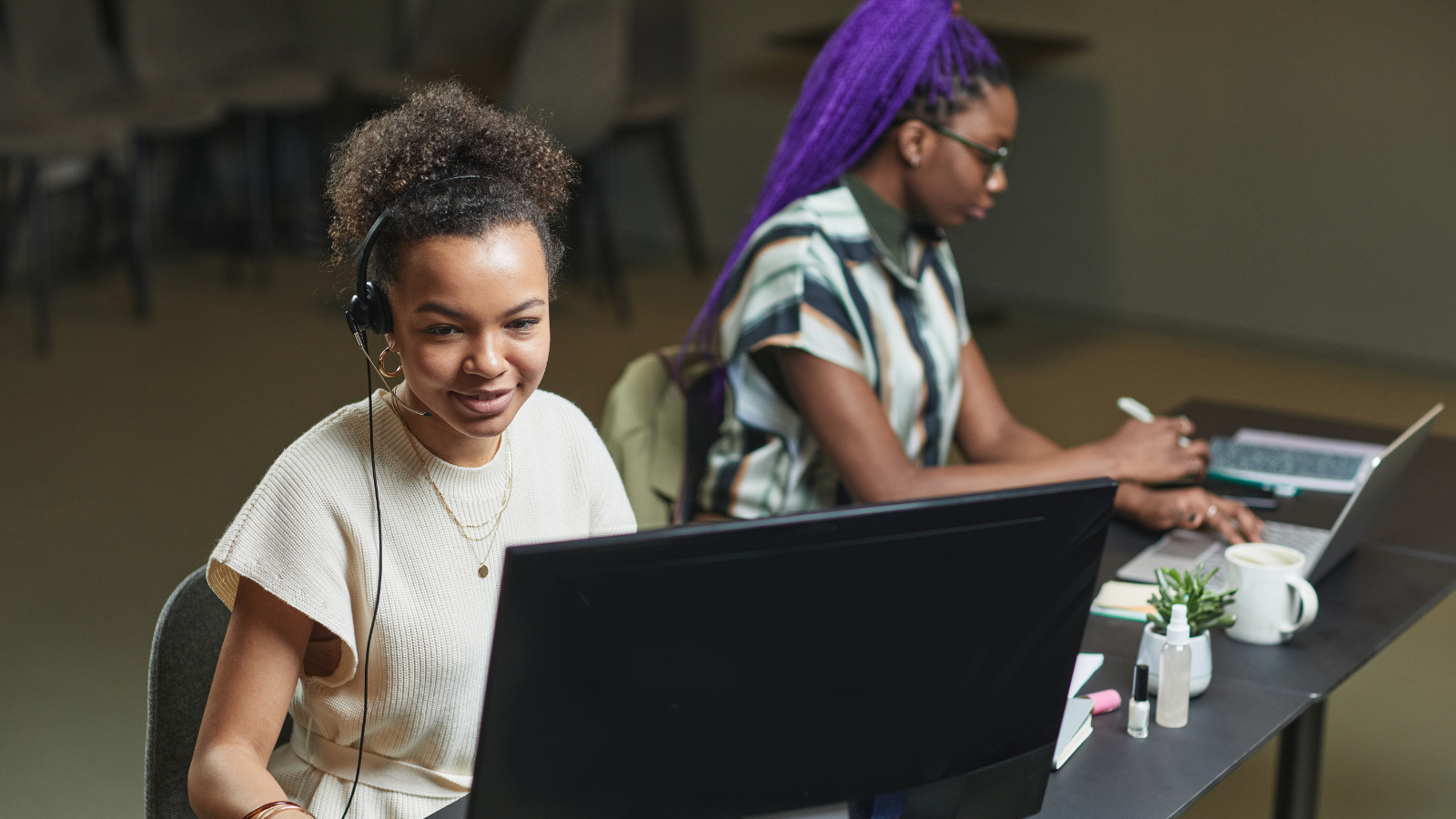 Two women using computer inside an office